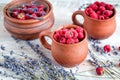 Raspberry in pottery cup with lavander on wooden background