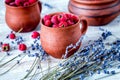 raspberry in pottery and lavender flowers on rustic background