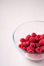 Raspberry red berries in transparent glass bowl plate tasty sweet bright on white background copy space macro Royalty Free Stock Photo