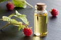 Raspberry seed oil in a bottle with fresh raspberries