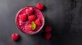 Raspberry smoothie in a glass on a black background, top view