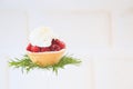 Raspberry tartlet with rosemary decoration on white background.