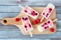 Raspberry vanilla popsicles on a paddle board over wood