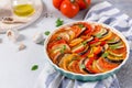 Ratatouille casserole on white background. Colorful layers of fresh summer vegetables: zucchini, eggplant, tomatoes and potatoes. Royalty Free Stock Photo