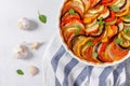 Ratatouille casserole on white background. Colorful layers of fresh summer vegetables: zucchini, eggplant, tomatoes and potatoes. Royalty Free Stock Photo