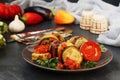 Ratatouille is located on a plate on a dark background. Baked vegetables: aubergines, zucchini and tomatoes