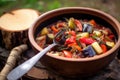 ratatouille served in a rustic camping bowl with a wooden spoon