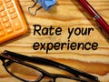 Rate your experience,text on wooden with calculator,pen,paper clips and glasses.