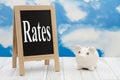 Rates message standing chalkboard with a piggy bank with clear sky