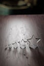 Rating - five transparent acrylic glas stars in different sizes arranged by size on a wooden table Royalty Free Stock Photo