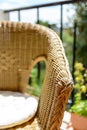 A rattan armchair with cushion on a sunny balcony