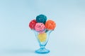 Rattan balls in form of ice cream scoops in glass cup on blue background minimalistic concept. Royalty Free Stock Photo