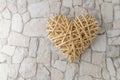 Rattan binded wooden heart on beige grey mosaic stone background Royalty Free Stock Photo