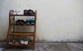 Rattan Shoe rack and shoes with beige cement walls in the background.