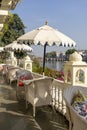 Rattan table and chairs under an umbrella in a street cafe on the shore near the lake in Udaipur, Rajasthan, India Royalty Free Stock Photo