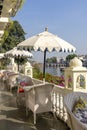 Rattan table and chairs under an umbrella in a street cafe on the shore near the lake in Udaipur, Rajasthan, India Royalty Free Stock Photo