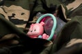 Rattle toy and baby bottle on military uniform, close up. Love and war concept Royalty Free Stock Photo