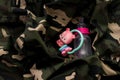 Rattle toy and baby bottle on military uniform, top view. Love and war concept Royalty Free Stock Photo