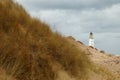 Lighthouse behind sand dunes