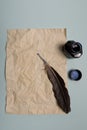 Raven feather, inkwell and old yellowed paper on red background. Copy space