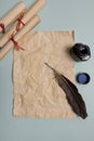 Raven feather, inkwell and old yellowed paper on red background. Copy space Royalty Free Stock Photo