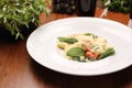 Ravioli pasta in white cream sauce with green leaves ,tomatoes and grated cheese, on a white plate, selective focus. Royalty Free Stock Photo