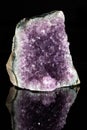 Raw amethyst stone on a black reflective background. Royalty Free Stock Photo