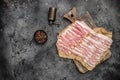 Raw bacon, bacon strips meat slice thin slicing pork fat meal on a dark background, ketogenic diet, place for text, top view