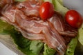 Raw bacon slices on lettuce leaves. Royalty Free Stock Photo