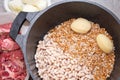 Raw Beef Being Added To A Saucepan Of Potatoes, Onion, Pearl Barley, Beans And Wheat Grains. Royalty Free Stock Photo