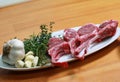 Raw beef bone rib-eye steak on a plate with onion, garlic and garnish ready to cook on a wooden table Royalty Free Stock Photo