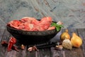 Raw beef bones in round clay bowl on wooden table decorated with vegetables and spices, vintage hunter knife. Beef selection for b Royalty Free Stock Photo