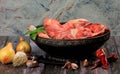 Raw beef bones in round clay bowl on wooden table decorated with vegetables and spices, vintage hunter knife. Beef selection for b Royalty Free Stock Photo