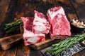 Raw beef calf short ribs meat on a butcher cutting board with cleaver. Dark wooden background. Top view Royalty Free Stock Photo