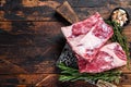 Raw beef calf short ribs meat on a butcher cutting board with cleaver. Dark wooden background. Top view. Copy space Royalty Free Stock Photo