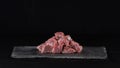 Raw beef, cubed and sprinkled with spices, on a slate and black background