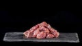 Raw beef, cubed and sprinkled with spices, on a slate and black background