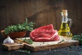 Raw beef fillet on a cutting board, thyme, olive oil. Ingredients for the preparation of stacks.