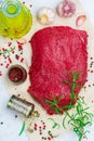 Raw beef. Fresh organic meat and spices on the marble table. Salt, pepper, garlic, rosemary and olive oil. We prepare a delicious
