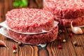 raw beef meat burger steak cutlets, dry pepper and garlic on rural wooden background