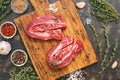 Raw beef meat on a cutting board with herbs and spices. View from above.