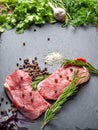 Raw beef meat and spices. Top view slices of fresh raw meat, rosemary and fresh herbs on a black slate stone plate. Preparing and Royalty Free Stock Photo