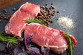 Raw beef meat. Two slices of fresh raw meat, rosemary and fresh herbs on a black slate stone plate. Preparing and marinating Royalty Free Stock Photo