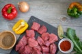 Raw beef stew on slate stone with spices, herbs, various peppers and onion on wooden table Royalty Free Stock Photo