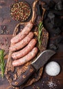 Raw beef and pork sausage on old chopping board with vintage knife on dark wooden background.Salt and pepper with rosemary Royalty Free Stock Photo