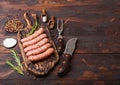 Raw beef and pork sausage on old chopping board with vintage knife and fork on dark wooden background.Salt and pepper with