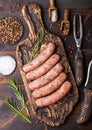 Raw beef and pork sausage on old chopping board with vintage knife and fork on dark wooden background.Salt and pepper with Royalty Free Stock Photo