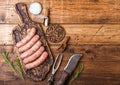 Raw beef and pork sausage on old chopping board with vintage knife and fork on wooden background.Salt and pepper with rosemary.