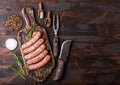 Raw beef and pork sausage on old chopping board with vintage knife and fork on dark wooden background.Salt and pepper with Royalty Free Stock Photo