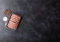 Raw beef and pork sausage in plastic tray with salt and pepper on black background. Space for text Royalty Free Stock Photo